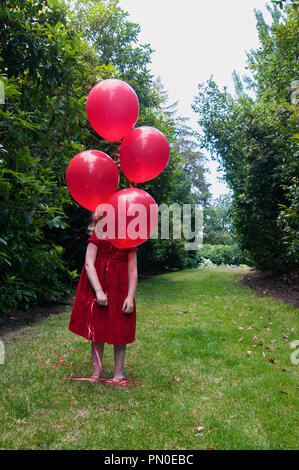 Ein junges Mädchen mit roten Ballons Stockfoto