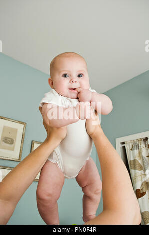 Eine Frau mit ihrem 6 Monate alten Baby Mädchen, ihren Finger in den Mund, weil sie Kinderkrankheiten ist. (Sechs Monate) Stockfoto