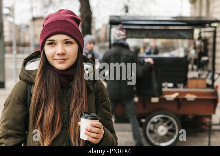 Ein Mädchen Getränke Kaffee aus einer Tasse auf der Straße in Prag bei kühlem Wetter. Die üblichen städtischen Alltag. Stockfoto