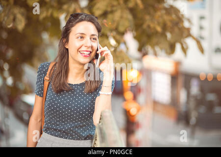 Junge, lächelnde Frau ruft auf dem Handy Stockfoto