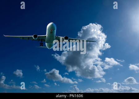 Eine künstlerische skyscape Ansicht eines kommerziellen Passagierflugzeugen fliegen in einem leuchtenden Blau des Himmels, mit hellen Weiß gefärbte geblähte Cumulonimbuswolken Stockfoto