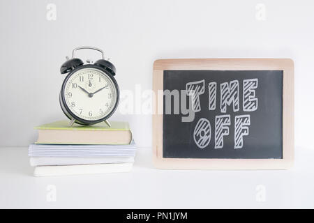 Wecker auf einem Stapel Bücher Neben eine Tafel mit dem Text mal aus an sie schrieb. Leere Raum für Editor's Text. Stockfoto