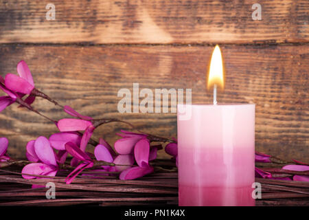 Dekorative ombre Lila aromatische Kerze mit Flamme und Filialen mit Blume auf Holz- Hintergrund. . Beauty Spa Behandlung und Konzept entspannen. Nahaufnahme Stockfoto