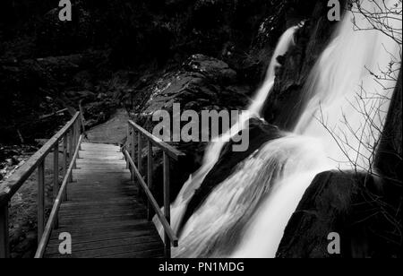 Eine Brücke überquert ein Wasserfall in den Rocky Mountains. Stockfoto