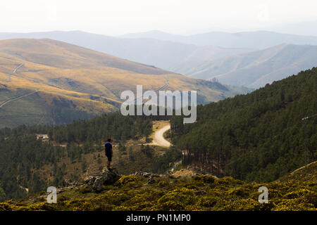 Ein Mann betrachtet eine Straße entlang die Berge in der Ferne. Stockfoto