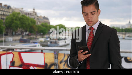 Erfolgreiche Latino männlichen Kontrollen telefonische Nachrichten auf Brücke in Paris Stockfoto