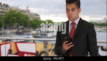 Erfolgreiche Latino männlichen Kontrollen telefonische Nachrichten auf Brücke in Paris Stockfoto