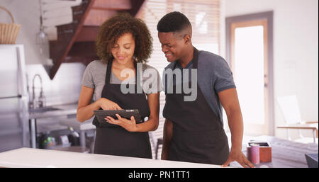 Schwarzer Mann und Frau plan Ihr Rezept auf ihren Tablet Stockfoto