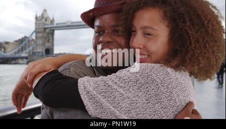 Glückliche junge afrikanische amerikanische Paar Lächeln und Umarmung von der Tower Bridge Stockfoto