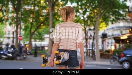 Ansicht der Rückseite des jungen Hipster weibliche Ihr Skateboard auf Paris Street Holding Stockfoto