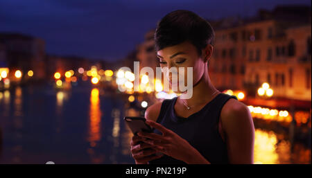 Hübsche schwarze Frau in Venedig Italien reisen liest ihr Handy Nachrichten lächelnd Stockfoto