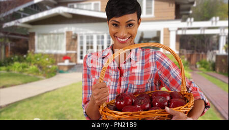 Lächelnd schwarze weibliche Holding Obstkorb außerhalb Home werfen Apfel in der Hand Stockfoto