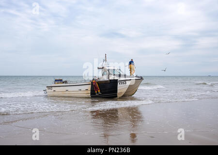Fischer an Land in ihrem Boot auf den Strand bei Cromer, Norfolk, Großbritannien Stockfoto