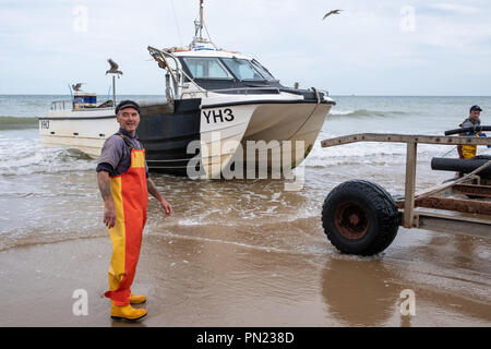 Fischer an Land in ihrem Boot auf den Strand bei Cromer, Norfolk, Großbritannien Stockfoto