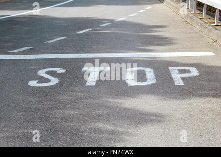 Stop-Schild auf Asphalt, lackiert Detail einer Straße und Straße. Stop Schild, Warnlampe "Stop" auf dem Asphalt. Stockfoto