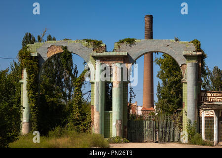 Mauern eines alten, verlassenen Fabrik mit einem Schornstein. Eine verlassene Fabrik mit einem hohen Stein. Pompöse gewölbten Eingang.. Stockfoto