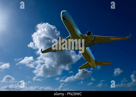 Eine künstlerische skyscape Ansicht eines kommerziellen Passagierflugzeugen fliegen in einem leuchtenden blauen Himmel mit hellen, weißen Cumulonimbuswolken. Sydney Stockfoto