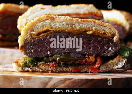In der Hälfte der Angus Burger im kornbrötchen mit Tomaten, Salat und Relish Cheddar Stockfoto