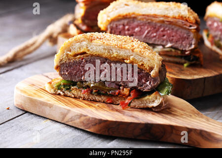 In der Hälfte der Angus Burger im kornbrötchen mit Tomaten, Salat und Relish Cheddar Stockfoto
