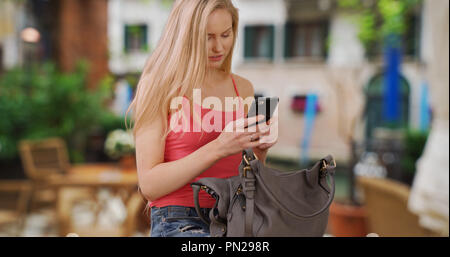 Blond weißes Mädchen nimmt Handy von Geldbörse in Venedig Italien Stockfoto