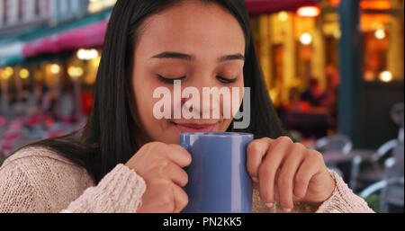 Smiling Hispanic Mädchen genießt eine Tasse Kaffee in einem Cafe in Brügge Stockfoto