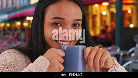 Smiling Hispanic Mädchen genießt eine Tasse Kaffee in einem Cafe in Brügge Stockfoto