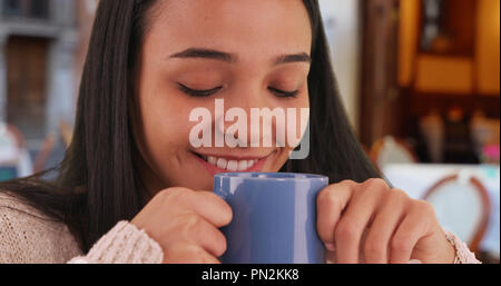 Lächelnd Latina geniesst den Duft von Kaffee in einem Cafe Stockfoto