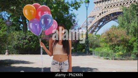 Lonely Latina hält ein Bündel Luftballons vor dem Eiffelturm Stockfoto