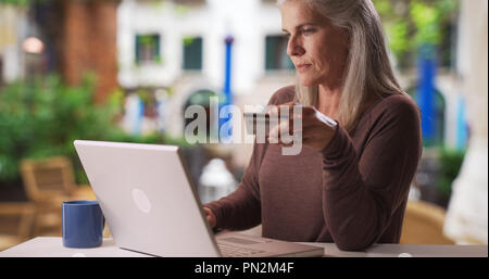Reifen kaukasische Frau Arten Kreditkarteninformationen auf Laptop außerhalb Stockfoto