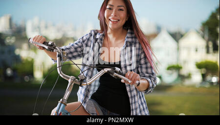 Japanische lächelnde Frau mit ihrem Fahrrad im Park Stockfoto
