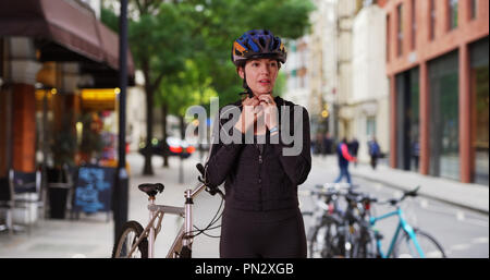 Sportliche Frau mit dem Fahrrad unter Bruch von Reiten in städtischen Umgebung Stockfoto