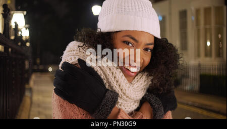 Gerne afrikanische amerikanische Frau, die versucht, warm auf kalt Winter Nacht in der Stadt zu halten. Stockfoto