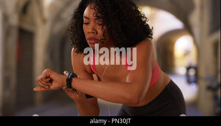 Schwarze Frau Jogger durch Florenz stoppt, fitness Tracker zu prüfen. Stockfoto