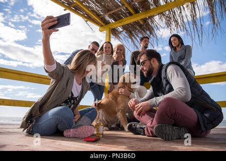 Happy Gruppe von Freunden heraus hängen im Beach House, das Spaß und Bier trinken auf Herbst Tag Stockfoto