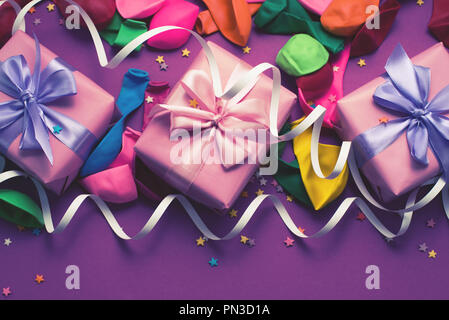 Festliche Hintergrund violett Material bunte Luftballons luftschlangen Konfetti drei Boxen Geschenk. Ansicht von oben flach kopieren Raum toning Stockfoto