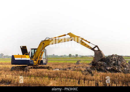 Bagger Baggerlader, die in den Graben ein Boden der postharvest-Bereiche in den Reisfeldern zu einstellen. Landwirtschaft Maschinen für die moderne Landwirtschaft Indus Stockfoto