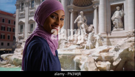 Junge muslimische Frau in Rom Italien reisen steht durch den Trevi-brunnen lächelnd Stockfoto