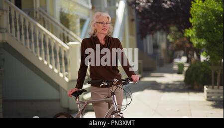Weiße Frau Senior auf dem Fahrrad draußen im schönen, ruhigen Nachbarschaft Stockfoto