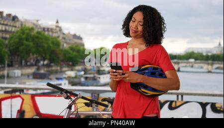 Afrikanische Frau, die mit dem Fahrrad in Paris hört Sms auf Handy senden Stockfoto