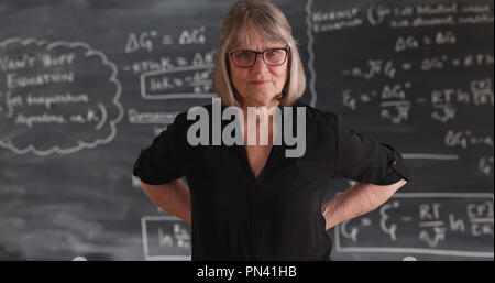 Alte ältere Frau Lehrerin mit ernsthaften Haltung vor der Tafel posing Stockfoto