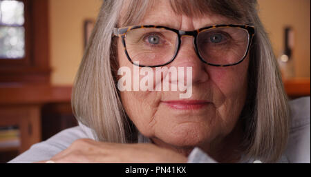 In der Nähe der düsteren ältere Frau Tragen von Brillen an Kamera drinnen auf der Suche Stockfoto