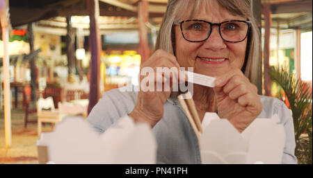 Portrait von Happy senior woman reading Fortune nach dem Essen chinesisch Essen außerhalb Stockfoto