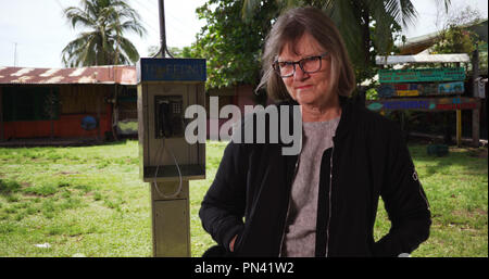 Ältere Frau mit Händen in den Taschen an der Kamera in der Nähe von Telefon in Costa Rica Stockfoto