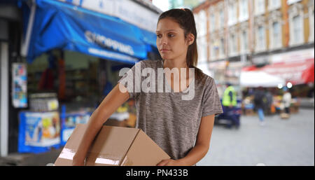 Düstere junge Frau in England, die Verpackung auf der Straße Stockfoto