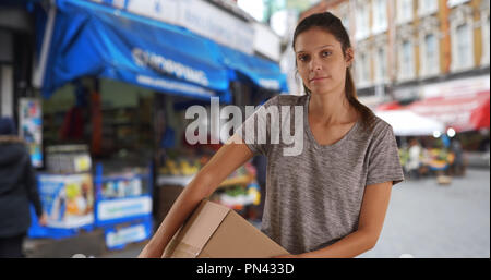 Düstere junge Frau in England, die Verpackung auf der Straße Stockfoto