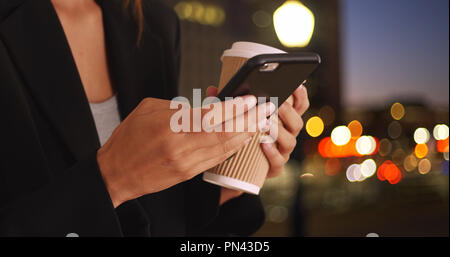 Womans Hände SMS mit Handy und Kaffeetasse in der Nacht Stockfoto