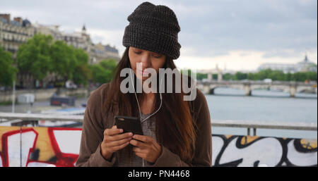 Touristische texting und Hören von Musik Streaming app mit Handy in Paris. Stockfoto