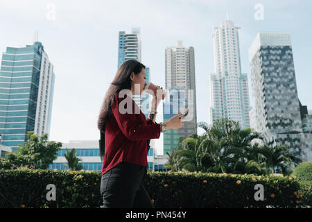 Chinesische Frau mit Telefon gehen und Kaffee trinken Stockfoto