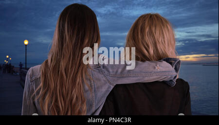 Zwei weibliche Freunde freundlich Moment miteinander an der Pier in der Dämmerung Stockfoto