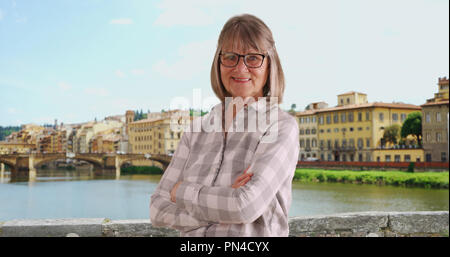 Senior glücklich lächelnde Frau mit verschränkten Armen außerhalb in Florenz Italien stehend Stockfoto
